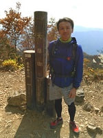 山頂標識の横に立つ人物