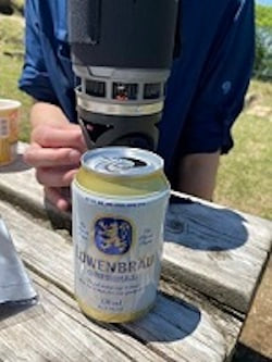 屋外テーブルに置かれた飲料缶と調理器具